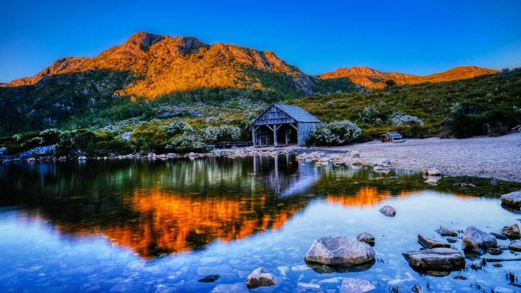 View of Cradle Mountain TAS with reflection on mountains on lake in foreground.