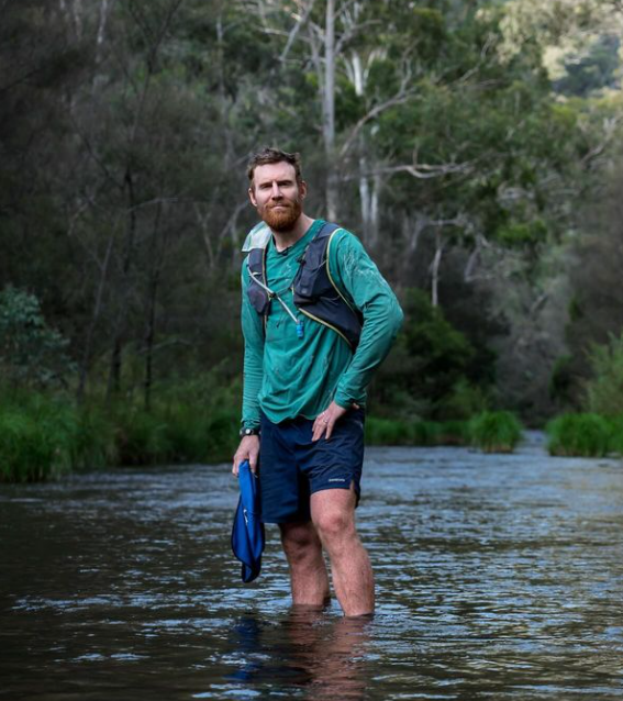 Beau Miles standing in the middle of a river in the Australian Bush